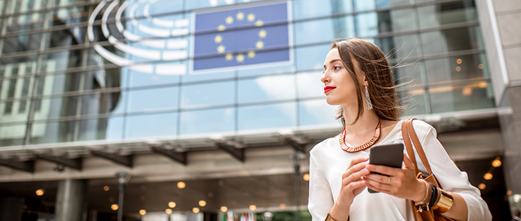 Young businesswoman standing with phone near the Parliament building of European Union in Brussel city